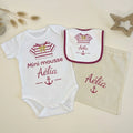 Coffret naissance personnalisé Mini Mousse de la marque Bébé d'Armor, comprenant un body blanc, un bavoir assorti et un pochon en coton beige, tous floqués au prénom d'Aélia avec un motif de marinière rose et une ancre marine, posés sur un fond épuré.