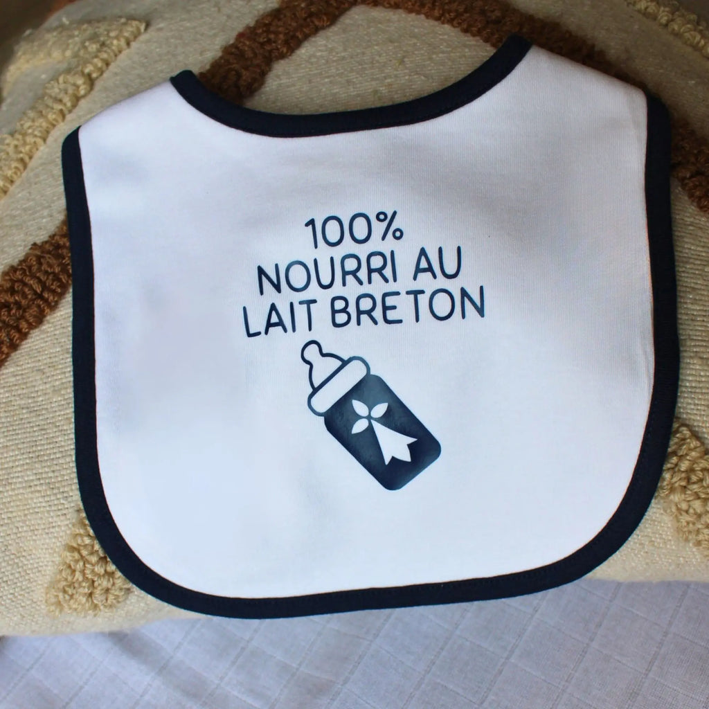 Bavoir blanc pour bébé avec liseré bleu marine, personnalisé avec l'inscription humoristique 100% nourri au lait breton et une illustration de biberon avec une hermine.