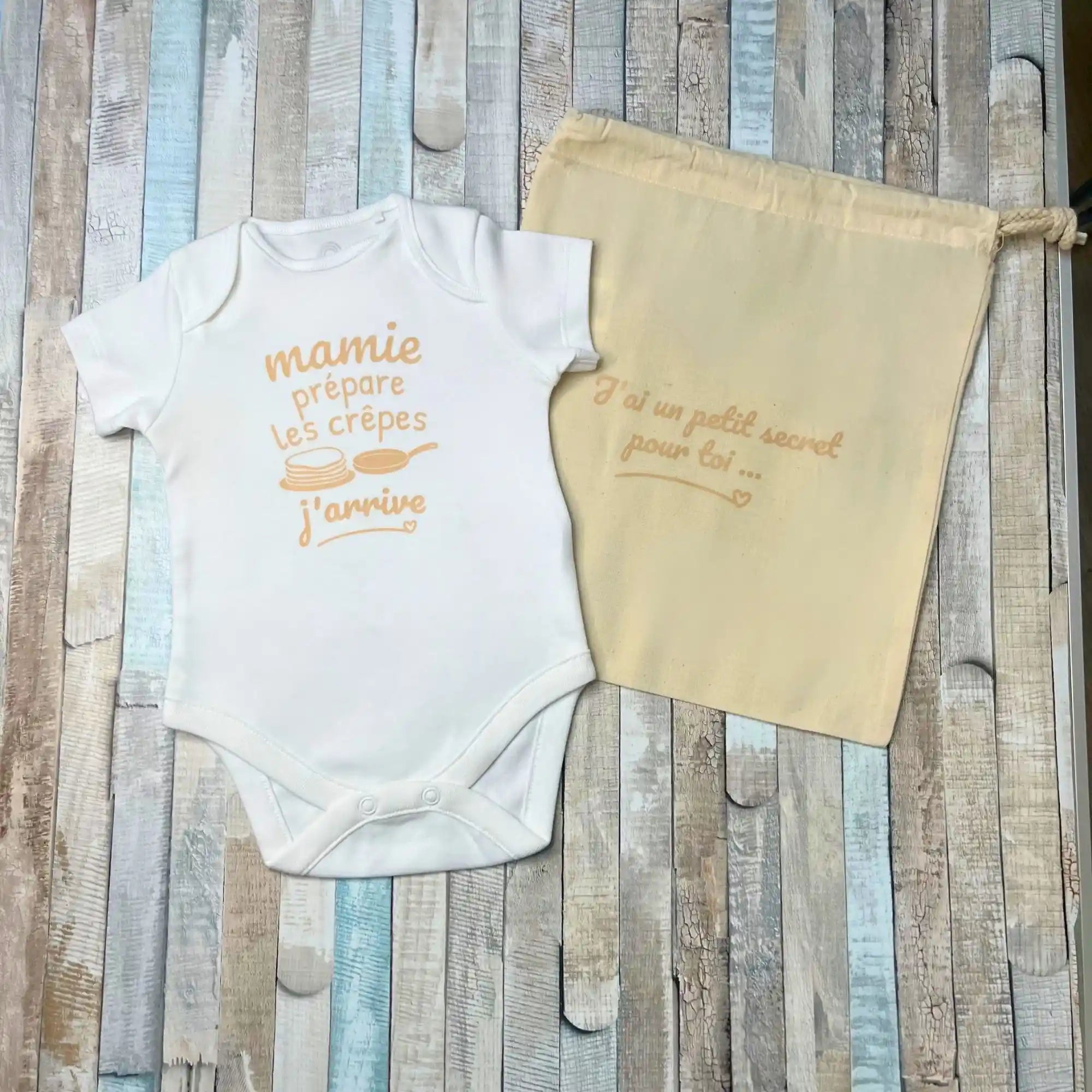 Body bébé blanc personnalisé « Mamie prépare les crêpes j'arrive » avec pochon en tissu « J'ai un petit secret pour toi » pour annonce de grossesse.
