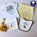 Kit de naissance breton personnalisé comprenant un body blanc 100% breton, un bavoir nourri au lait breton, un lange blanc et un pochon de rangement en tissu jaune.