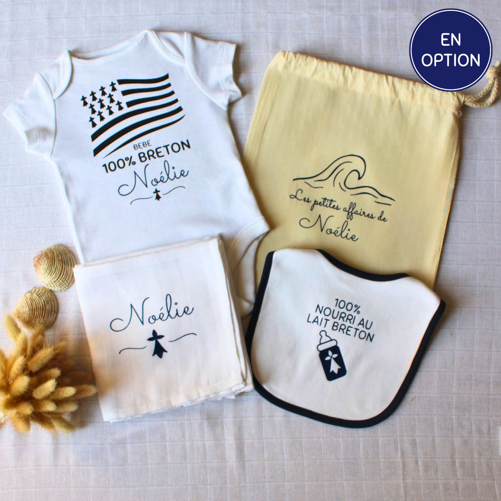 Kit de naissance breton personnalisé comprenant un body blanc 100% breton, un bavoir nourri au lait breton, un lange blanc et un pochon de rangement en tissu jaune.